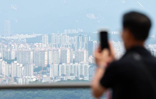 한 시민이 이날 서울 남산에서 바라면 서울 시내 아파트 전경을 스마트폰에 담고 있다. 연합뉴스