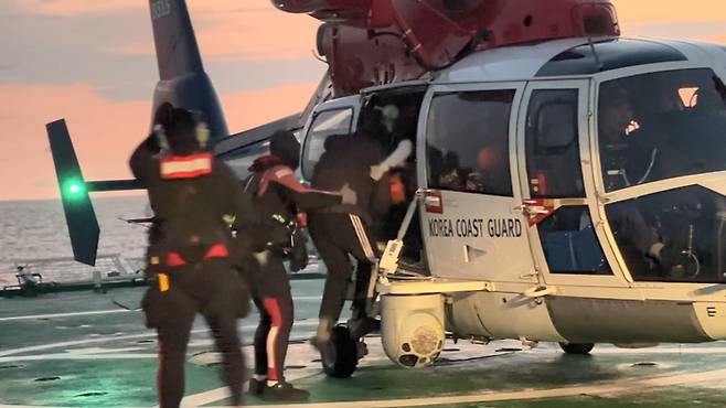 동해 해상에서 손목이 절단된 선원이 해경 헬기를 통해 긴급 이송되고 있다. 거센 바람과 파도 속에서도 해경 대원들이 신속하게 환자를 헬기에 태우고 있으며, 이 환자는 대구 W병원으로 옮겨져 6시간에 걸친 접합 수술을 받았다.<동해해경청 제공>