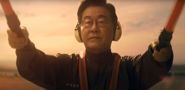 ‘세계가 경주로 향한다’ APEC 홍보영상에시 항공기 유도원으로 등장, 경광봉을 흔들고 있는 이재명 대통령. APEC 홍보영상 갈무리