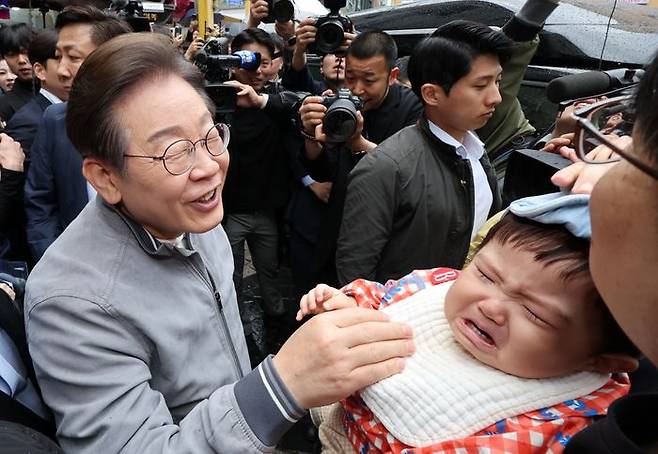 민심을 청취하는 '경청 투어'에 나선 이재명 더불어민주당 당시 대선후보가 지난 5월 3일 강원도 속초중앙시장에서 아이에게 인사하고 있다. ⓒ뉴시스