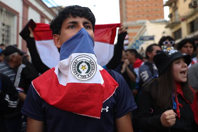 지난달 28일 파라과이 수도 아순시온에서 벌어진 시위에 참여한 한 청년 남성이 파라과이 국기로 얼굴을 가리고 있다. EPA 연합뉴스