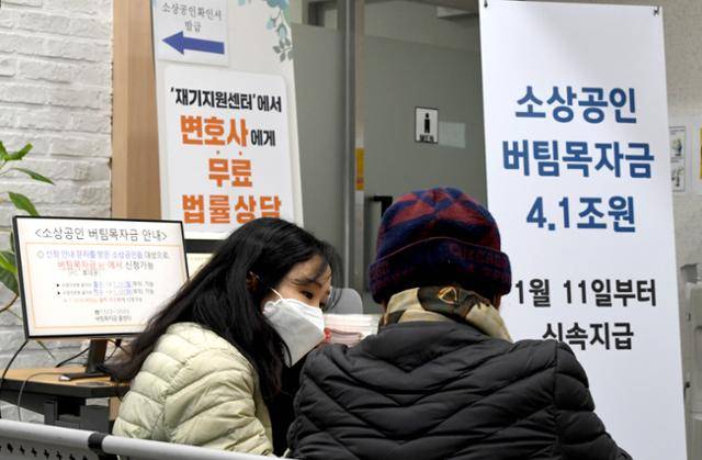 2021년 1월 11일 서울 중구 소상공인시장진흥공단 서울중부센터를 찾은 소상공인이 직원에게 버팀목자금 신청 방법을 안내받고 있다. 서재훈 기자