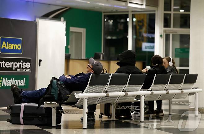 4일 새벽 독일 남부 뮌헨 국제공항에서 드론 출현으로 인해 공항 운영이 또다시 중단되자, 항공편 취소로 발이 묶인 승객들이 벤치에 앉아 휴식을 취하고 있다. 2025.10.4 ⓒ AFP=뉴스1