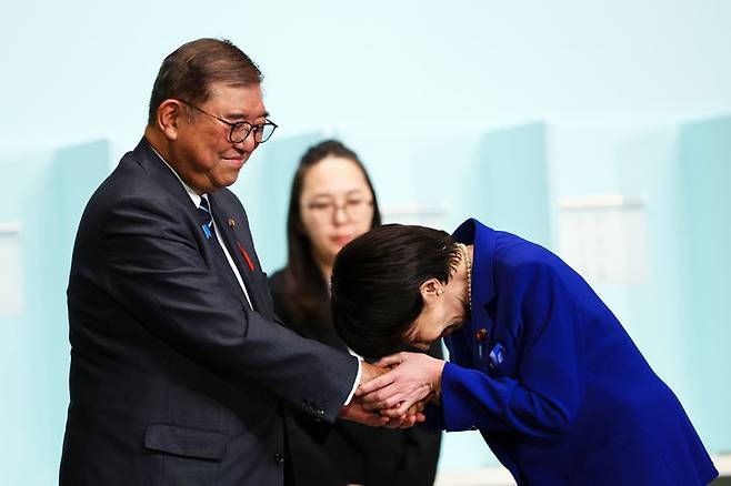 [도쿄=AP/뉴시스] 4일 일본 도쿄에서 열린 집권 자민당 총재 선거에서 승리한 다카이치 사나에(오른쪽) 신임 총재가 이시바 시게루 총리와 악수하며 고개를 숙이고 있다. 2025.10.04.