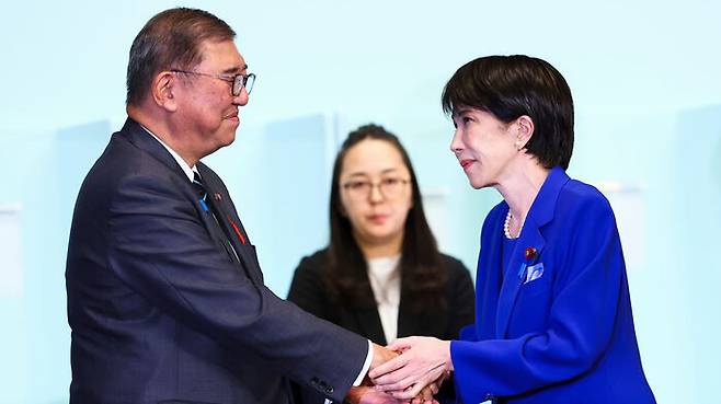 일본 집권 자민당의 새로 선출된 총재 다카이치 사나에(오른쪽)가 선거에서 승리한 뒤 이시바 시게루 총리와 악수하고 있다. (사진=AP, 연합뉴스)