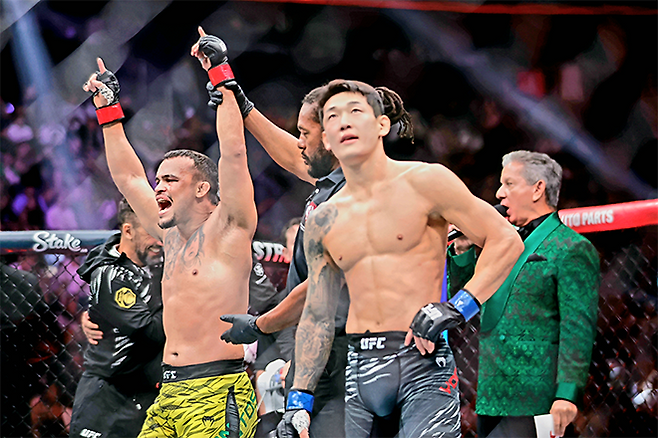 다니에우 구스타부 곤자가 산투스가 2025년 10월 미국 네바다주 패러다이스 티모바일 아레나 UFC 320 승리 선언을 들으며 감격하고 있다. 오른쪽은 UFC 데뷔 2연승 및 종합격투기 13연승 무산을 아쉬워하는 ‘좀비 주니어’ 유주상. 사진=AP=연합뉴스 제공