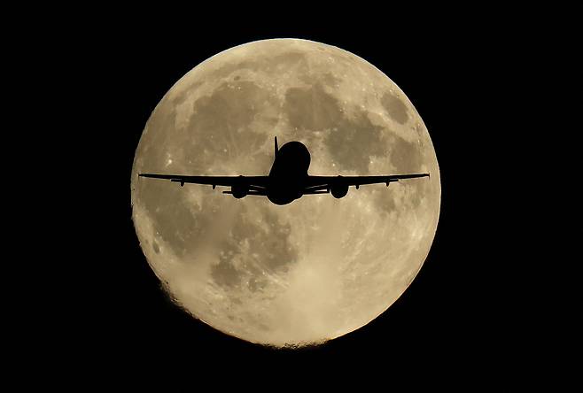 6일 한 여객기가 영국 런던 상공에 뜬 올해 첫 슈퍼문이자 '추수달'로 알려진 달을 지나고 있다./로이터 연합뉴스