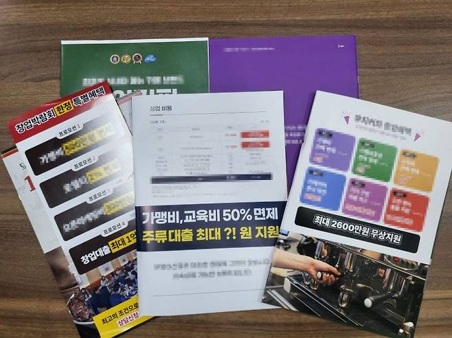 프랜차이즈 창업 박람회에서 프랜차이즈 본사가 나눠준 다양한 안내 책자들. 최대 2600만원까지 무상 지원이 된다거나 1억원까지 대출 지원이 가능하다고 안내하고 있다. 이현주 기자