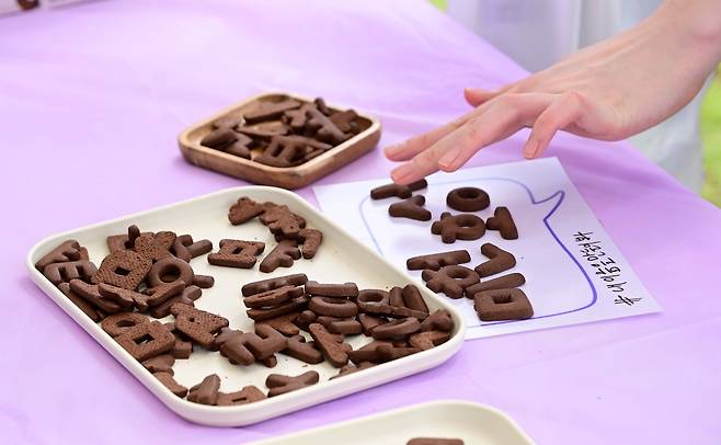 Participants create words using Hangeul-shaped cookies at the Kalphabets booth, a brand launched by Tyler Rasch and Nidhi Agrawal, during the Hangeul Goods Fair held at Sejong Lake Park on Thursday. (Lee Sang-sub/The Korea Herald)