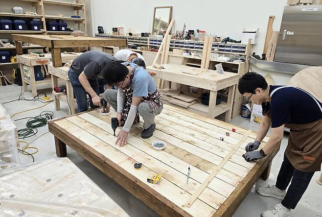 인테리어디자인과 성인학습자 과정 학생들과 평생교육원 가구반 회원들이 들마루를 제작하고 있다.[영남이공대 제공]