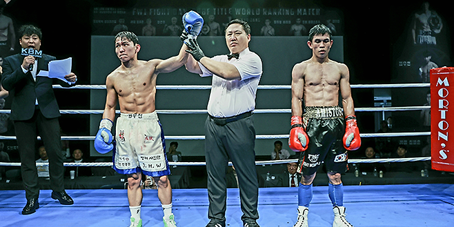 도전자 김우현이 2025년 10월 서울특별시 섬유센터 이벤트홀 사단법인 한국복싱커미션 KBM 밴텀급 타이틀매치 승리 선언을 받고 있다. 김우현은 세계복싱협회 슈퍼플라이급 아시아 챔피언을 지냈다. 오른쪽은 1차 방어 무산을 아쉬워하는 챔피언 조버 아미스토소. 사진=FINAL FLASH 제공