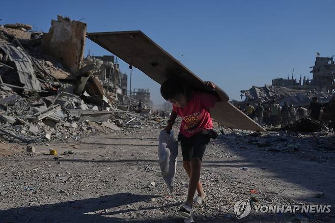 11일 가자시티에서 나무판을 들고 가는 팔레스타인 소년 [AP 연합뉴스 재판매 및 DB 금지]