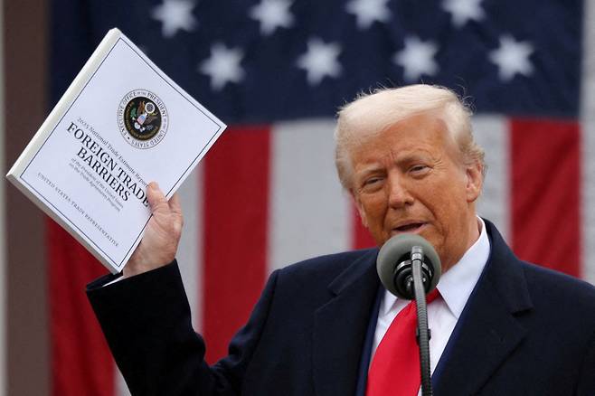 U.S. President Donald Trump holds a ″Foreign Trade Barriers″ document as he delivers remarks on tariffs in the Rose Garden at the White House in Washington on April 2. [REUTERS/YONHAP]