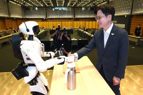 Industry Minister Kim Jung-kwan, right, shakes hands with a humanoid robot developed by Korean startup AeiROBOT during an event in central Seoul on Sept. 25. [YONHAP]