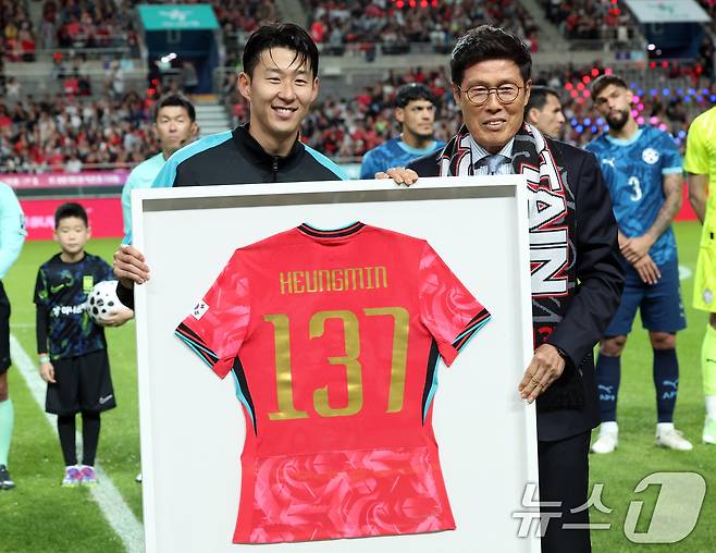 한국 남자 선수 A매치 최다 출전한 손흥민이 14일 오후 서울 마포구 서울월드컵경기장에서 열린 하나은행 초청 축구국가대표팀 친선경기 대한민국과 파라과이의 경기 시작 차범근 전 감독에게 기념 유니폼을 전달받고 기념촬영을 하고 있다. 2025.10.14/뉴스1 ⓒ News1 김명섭 기자