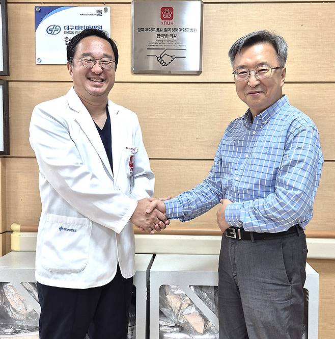 김영헌 (오른쪽) 울릉군 보건의료원장과 김창호 칠곡경북대학교병원 응급실장이  현판식후 악수를 나누고 있다.[울릉군 보건의료원 제공]