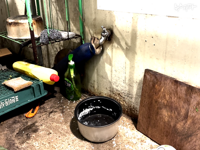 따우(가명) 씨 방문 앞 수돗가 바닥에 놓인 전기밥솥 내솥 안에 3분의 1 정도 물이 차 있다. 내솥에 붙은 흰 밥알들이 누군가 밥을 지어 먹으며 지내고 있음을 알린다.