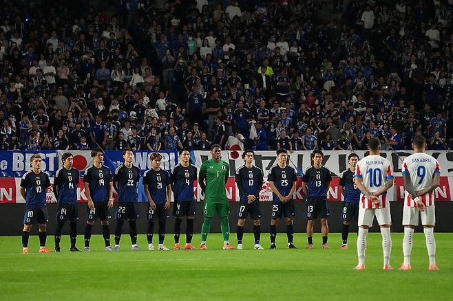 일본 축구대표팀 선수들이 10일 파라과이전에 앞서 그라운드 중간에 도열해 일본 축구 레전드 쿠니시게 가마모토를 추모하고 있다. Getty Images코리아