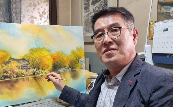 김해록 작가가 20일까지 창원 성산아트홀 제2전시실에서 '물빛으로 피워낸 경남의 아름다운 이야기들'이라는 주제로 제3회 개인전을 연다. 김 작가가 '가을빛에 물든 위양지'를 작업하고 있다. /김해록