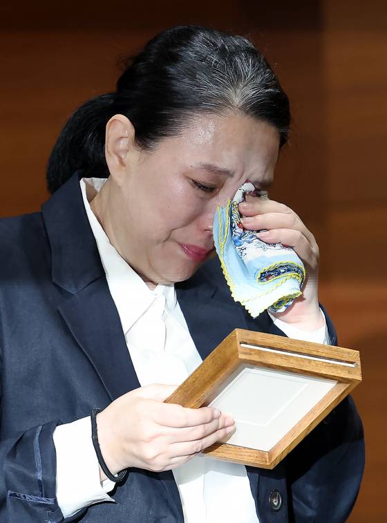직장 내 괴롭힘을 호소하며 스스로 목숨을 끊은 MBC 기상캐스터 오요안나의 어머니 장연미 씨가 안형준 MBC 사장에게 받은 고인의 명예 사원증을 안고 눈물을 흘렸다. 사진 뉴스1