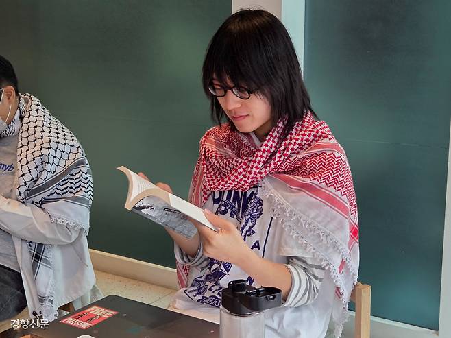 아랍 전통 스카프 케피예를 두른 시민이 지난 14일 서울 종로구 주한이스라엘대사관 건물 내 카페에서 책을 읽고 있다.