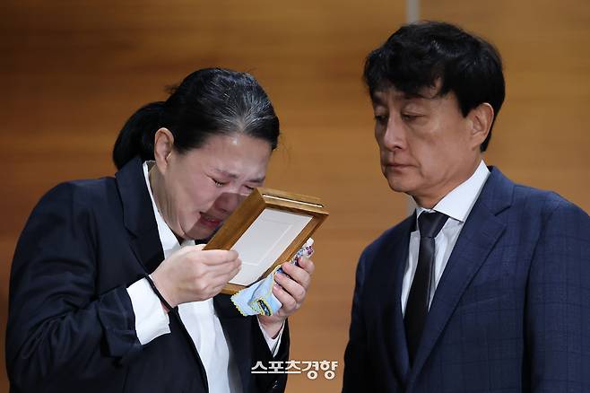 직장 내 괴롭힘을 호소하며 숨진 MBC 기상캐스터 고 오요안나 씨 어머니 장연미 씨가 15일 서울 마포구 상암동 MBC 사옥에서 열린 기자회견에서 안형준 MBC 사장으로부터 고인의 명예사원증을 받은 뒤 눈물을 흘리고 있다. 성동훈 기자