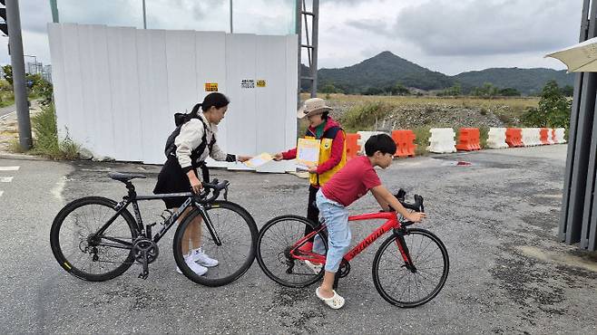 이날 자전거를 타고 국가상징구역을 찾은 모자가 중도일보 행사 리플렛을 받아들고 있다.