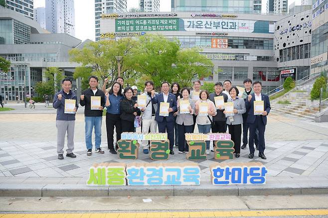 최민호 시장과 전광희 여사, 권영석 환경녹지국장과 정경용 보건환경연구원장, 김대곤 정책수석, 손경희 환경교육센터 상임대표 등이 이날 한마당 부스에서 '2025 국가상징구역 한바퀴' 리플렛을 들어 보이며 기념사진 촬영에 응하고 있다. 사진=세종시 제공.