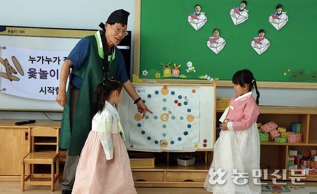 전통나눔 할아버지로 나선 김창교씨가 아이들에게 윷놀이 규칙을 설명하고 있다.