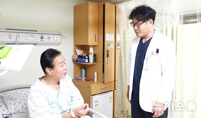 [포항=뉴시스] 송종욱 기자 = 포항세명기독병원 지역심뇌혈관질환센터 조재훈 부장(오른쪽)이 뇌경색 진단 후 혈전 제거술을 받고 후유증 없이 회복 중인 A(61)씨를 회진하고 있다. (사진=포항세명기독병원 제공) 2025.10.20. photo@newsis.com