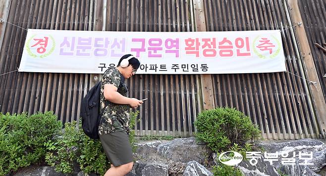 지난 7월 28일 오전 수원시 권선구의 한 아파트 입구에 걸린 신분당선 구운역 신설 확정 현수막 앞으로 시민이 지나가고 있다. 노민규기자