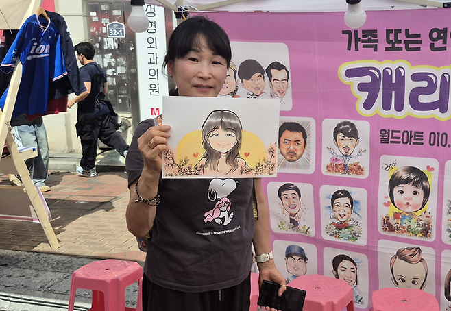 구미에서 대경선을 타고 동성로를 찾은 황애경(51) 씨가 놀장 축제의 캐리커처 부스에서 그려진 자신의 얼굴 그림을 들고 웃고 있다. 조윤화 기자