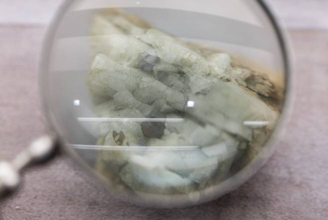 2025년 10월 14일 중국 베이징의 중국지질박물관에, 세륨(Ce)ㆍ란타넘(La)ㆍ네오디뮴(Nd) 등의 희토류 원소를 추출하는 광물인 모나자이트 샘플이 확대경 옆에 전시돼 있다./로이터 연합뉴스