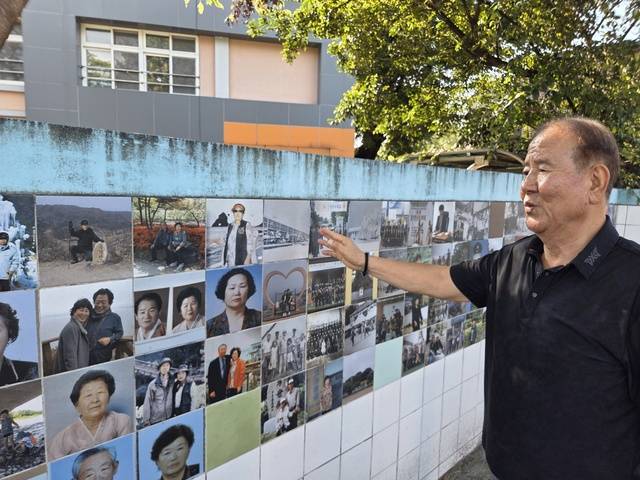 서석영씨가 장기중학교 타일벽화의 주민 사진을 가리키며 마을 이야기를 들려주고 있다.