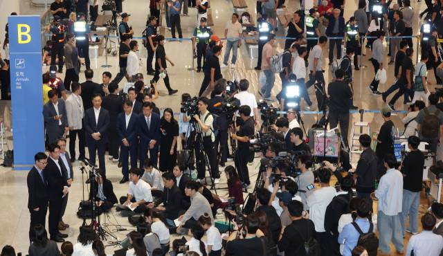 미국 이민당국에 의해 조지아주에 구금됐던 한국인 근로자들이 12일 인천국제공항 제2여객터미널 입국장을 나서는 동안 강훈식 대통령실 비서실장 등이 취재진과 인터뷰하고 있다. 연합뉴스