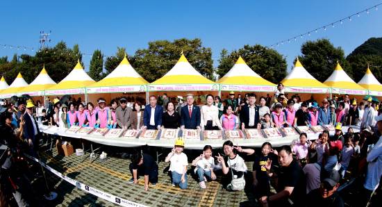 부자떡나눔 행사에서 참석자와 어린이들이 포즈를 취하며 사진을 찍고 있다.