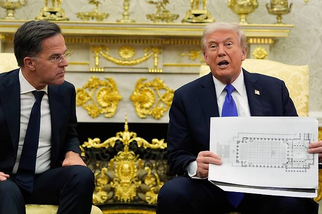 도널드 트럼프 미국 대통령이 22일(현지시각) 워싱턴 백악관 집무실에서 마르크 뤼터 나토(NATO·북대서양조약기구) 사무총장과 회담 중 새로운 백악관 연회장의 좌석 배치도를 들고 있다. 워싱턴/AP 연합뉴스