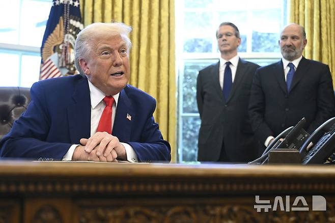 [워싱턴=AP/뉴시스] 도널드 트럼프 미 대통령이 지난 4월 9일(현지 시간) 대통령 행정명령에 서명한 뒤 기자들의 질문에 답하고 있다. 뒤에 스콧 베선트 재무장관과 하워드 러트닉 상무장관이 배석해 있다. 2025.10.23.