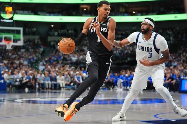 샌안토니오 스퍼스 빅토르 웸반야마가 23일(한국시간) 미국 텍사스주 댈러스의 아메리칸 에어라인스 센터에서 열린 2025~26 미국 프로농구(NBA) 정규시즌 댈러스 매버릭스와의 원정 경기에서 앤서니 데이비스를 제치고 있다. AP 연합뉴스