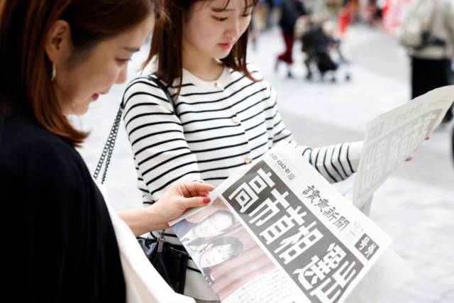 지난 21일 일본 도쿄에서 젊은 여성들이 다카이치 사나에 총리 선출 호외 신문을 읽고 있다./로이터연합뉴스