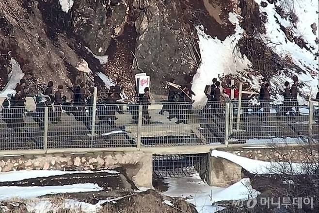 합동참모본부가 지난 3월27일 발표한 북한군 활동 모습. 사진은 북한군이 서부전선 감시초소(GP) 일대에서 작업도구와 '봉쇄'간판을 들고 이동하는 모습. / 사진=합동참모본부