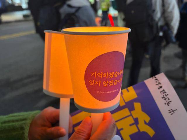 천주교정의구현사제단이 27일 서울 용산구 녹사평역 인근 광장에서 진행한 이태원 참사 3주기 추모 미사 중 한 시민이 촛불을 밝히고 있다. 이날 오후 6시 34분 이태원 거리에는 희생자 수와 같은 159개의 촛불이 켜졌다. 오후 6시 34분은 3년 전 참사 당일 상가 주인 박주희씨가 최초로 112신고를 한 시간이다. 연합뉴스