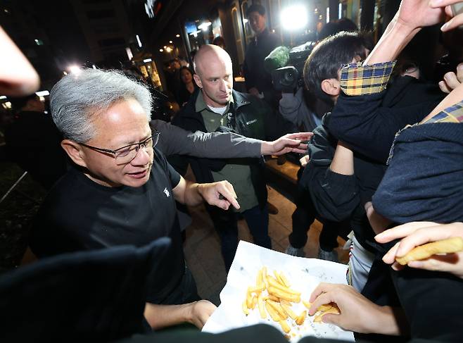 젠슨 황 엔비디아 최고경영자가 30일 서울 삼성동 한 치킨집에서 진행된 이재용 삼성전자 회장, 정의선 현대차그룹 회장과 치맥 회동 중 시민에게 치킨과 감자튀김을 나눠주고 있다. 연합뉴스