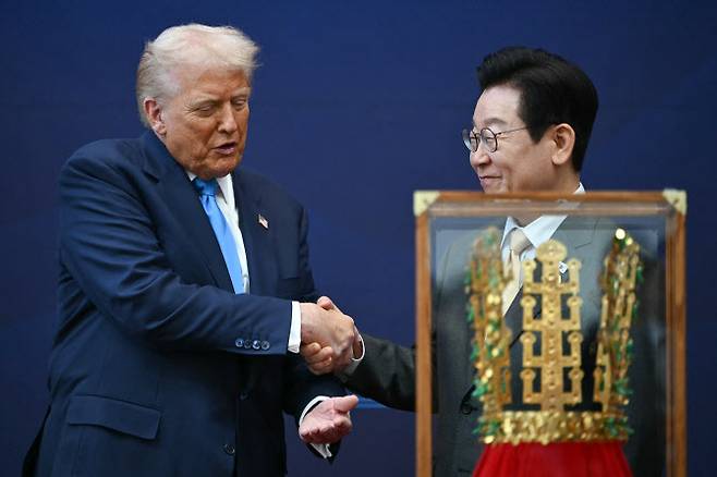 도널드 트럼프(왼쪽) 미국 대통령이 29일 경주 국립경주박물관에서 이재명 한국 대통령으로부터 고대 신라 금관 모형인 황금 왕관을 선물로 받으며 악수를 나누고 있다. (사진=AFP)