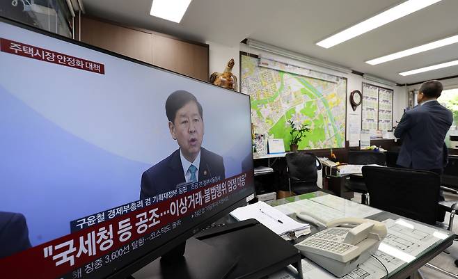 A television in a real estate agency in Seoul airs a news report on the government’s new housing market stabilization measures on Oct. 15. All 25 districts of Seoul and 12 areas in Gyeonggi Province were recently designated as regulated zones, including adjustment and speculation-prone areas. [YONHAP]