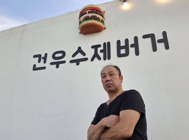 자신의 이름을 딴 수제버거 집 앞에서 포즈를 취한 김건우.   김건우 제공