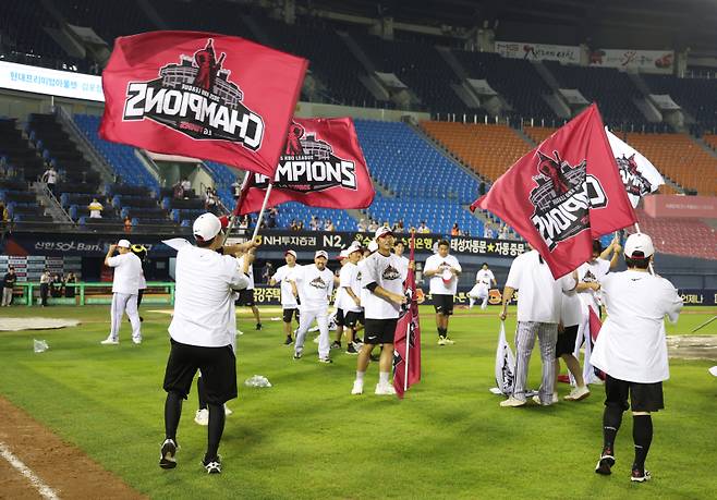 LG 선수단이 지난 1일 한화의 패배로 정규시즌 우승을 확정 지은 뒤 우승 깃발을 들고 세리머니를 하고 있다. 지난 1일 잠실 NC전 패배 후 1시간여 지난 터라 관중석이 텅 비어 있다. 사진=구단 제공
