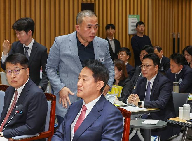 정치 브로커 명태균 씨가 23일 서울 중구 서울시청에서 열린 2025년 국회 행정안전위원회 국정감사에서 증인석으로 향하며 오세훈 서울시장 뒤로 지나가고 있다. [연합뉴스]