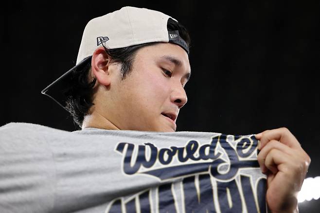 오타니 쇼헤이가 2일 캐나다 토론토 로저스센터에서 열린 토론토 블루제이스와의 2025 메이저리그 월드시리즈 7차전에서 승리한 뒤 우승 티셔츠를 보고 있다.  토론토 | AFP연합뉴스