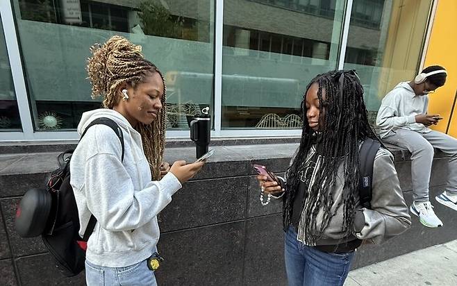 미국 뉴욕시 맨해튼 미드타운 웨스트지역 비컨고등학교에 재학중인 라토야 존슨(사진 왼쪽) 학생이 등교 전 스마트폰으로 하루 일과를 점검하고 있다.